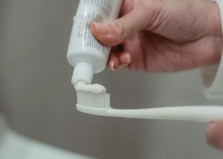 person putting some toothpaste on toothbrush