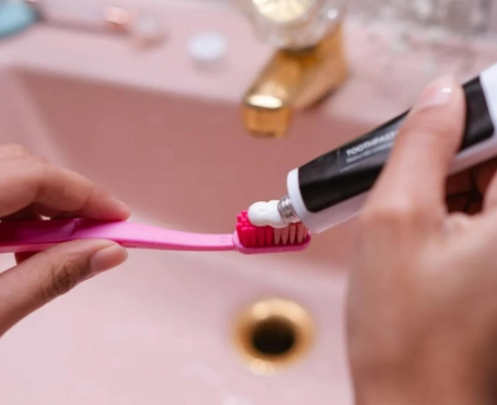 person putting toothpaste on toothbrush
