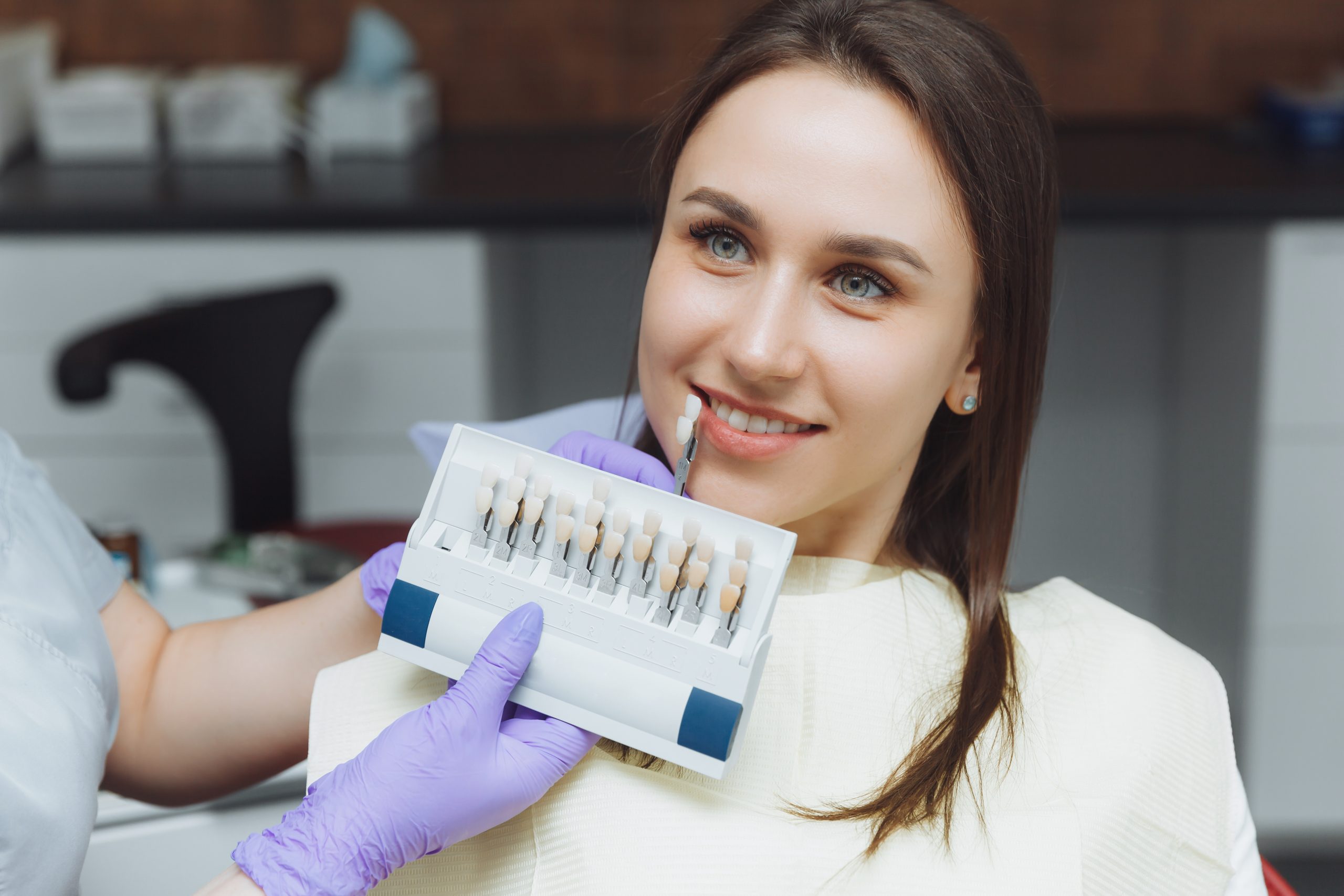 Selection of the correct tooth color for professional cosmetic whitening at the dentist. the doctor selects the teeth for the patient.
